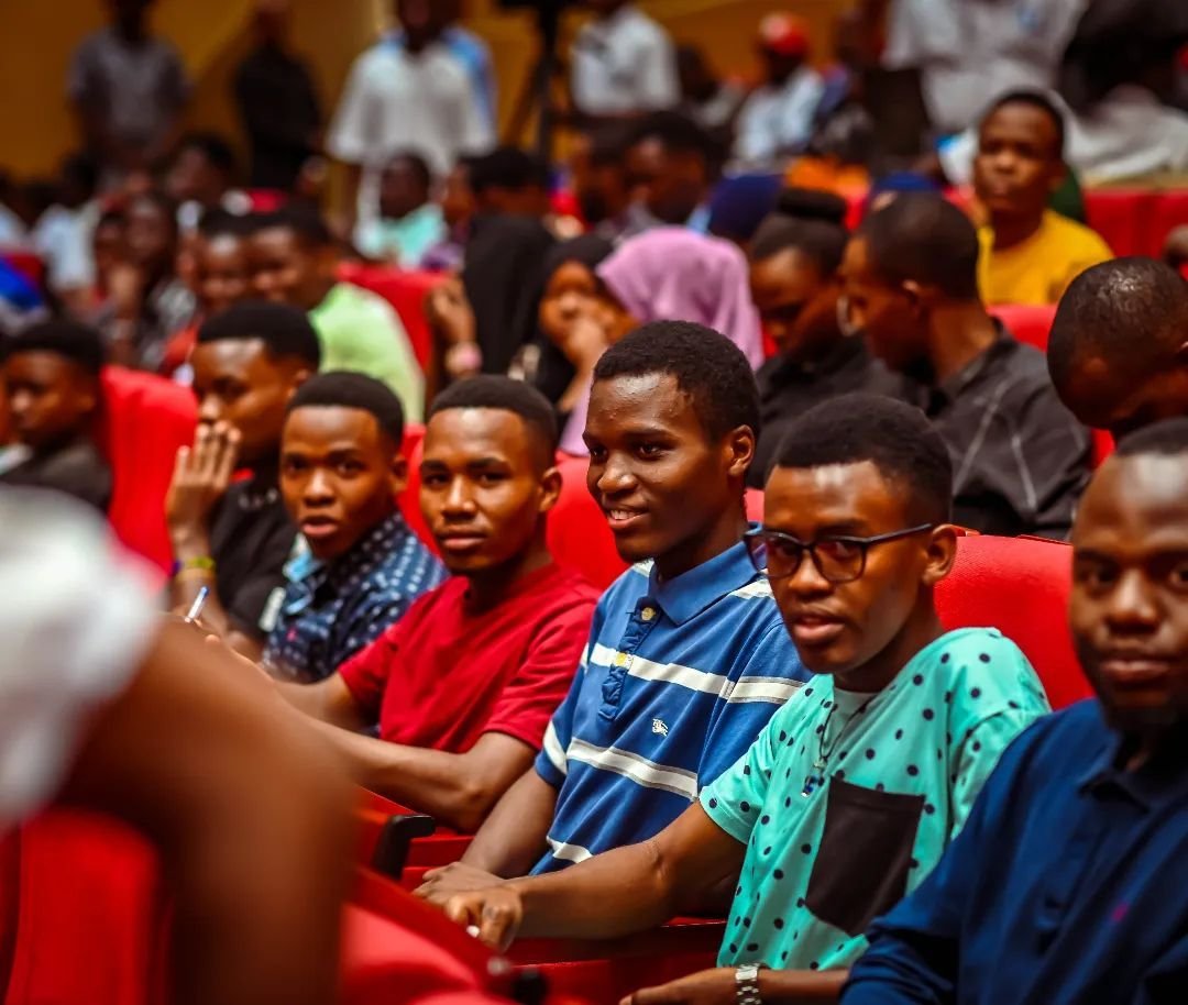 Young people seated in the audience of an event, some smiling